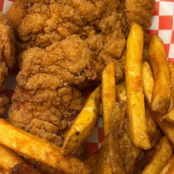 Crispy fried chicken tenders and golden french fries served in a red and white checkered basket.