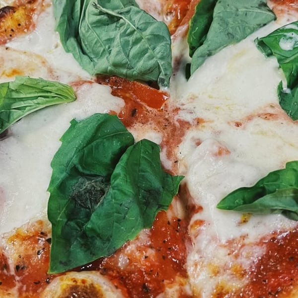 Close-up of a Pizza Nation Margherita pizza with melted mozzarella, red sauce, and fresh basil.